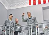 (From left) Capt. Daniel Luczak of the Air Force Life Cycle Management Center (AFLCMC) and Master Sgt. Matthew Weede of Air Force Materiel Command look on as 2nd Lt. Max Reilly of AFLCMC prepares to launch his paper airplane during a fundraiser for the Mi