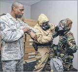 Evaluator Senior Master Sgt. Stephen Christian of the 711th Human Performance Wing counts down the “fall dead” time as Tech. Sgt. Kristopher McKay assists Senior Airman Rebecca Shelly, both with the 88th Medical Group, into her protection suit during a de